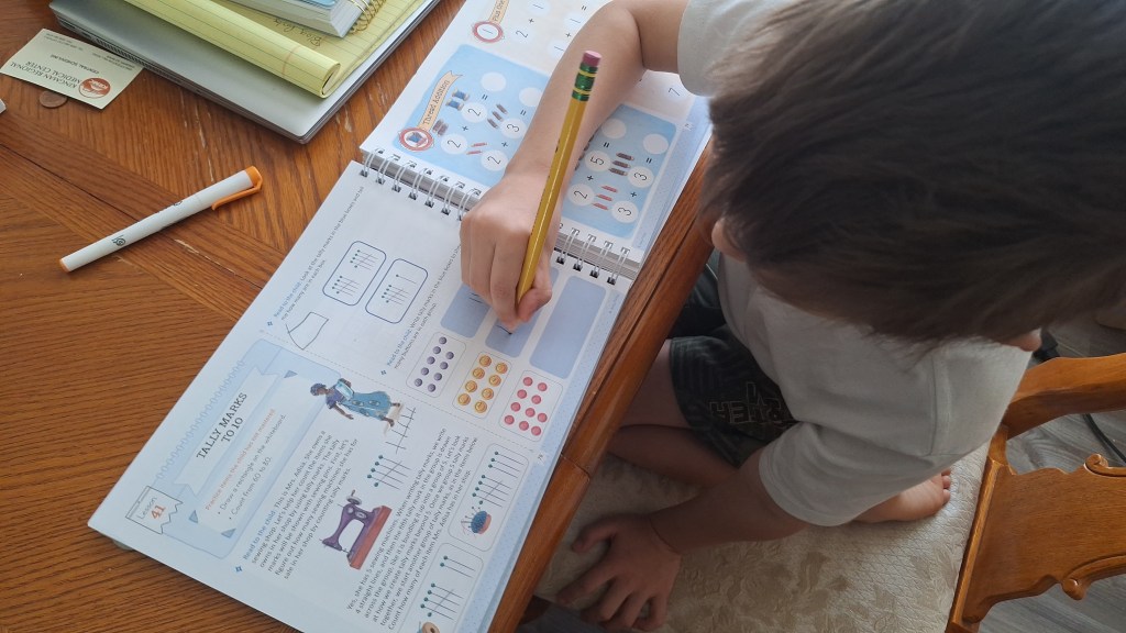 boy using the Good and the Beautiful math curriculum for homeschooling